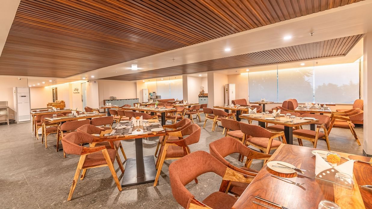 Interior of The Bridge restaurant at Clarks Inn Suite Jaipur featuring tables and chairs arranged with a view of the outside through large windows