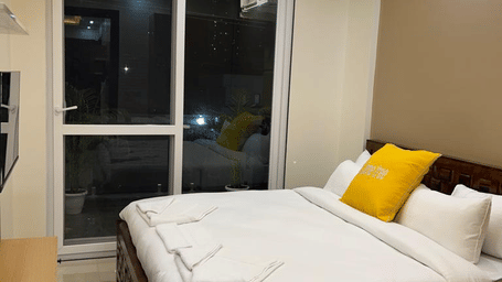 Bedroom of Lime Tree Hotels & Service Apartment Private Limited featuring yellow cushions, a curtained window, and cove lighting.