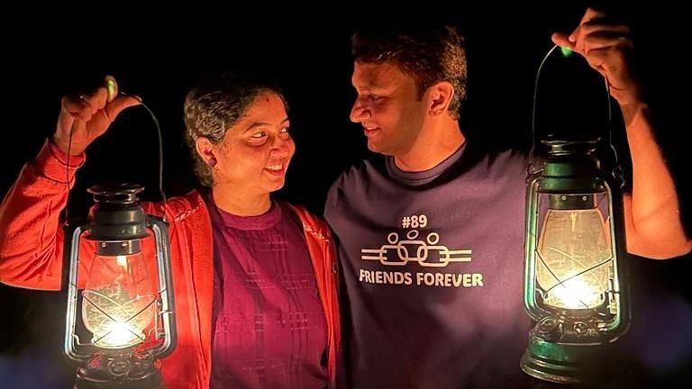 A couple looking at each other while holding lanterns in the dark - Evergreen County