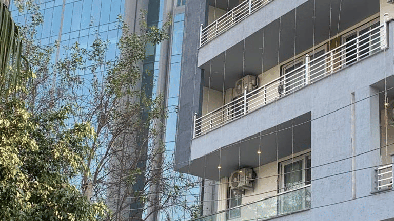 Exterior of Lime Tree Hotel Near 32nd Avenue showing a multi-storey building with balconies, white railings, and a glass office tower behind