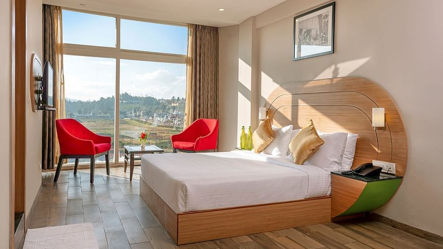 An image of a bedoom where natural light is seeping in through the glass window | Mango HIll Central, Ooty
