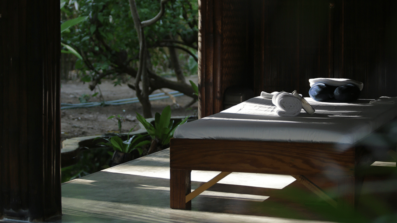 Massage table set outdoors facing the beach under the shade at Flower Island Resort.