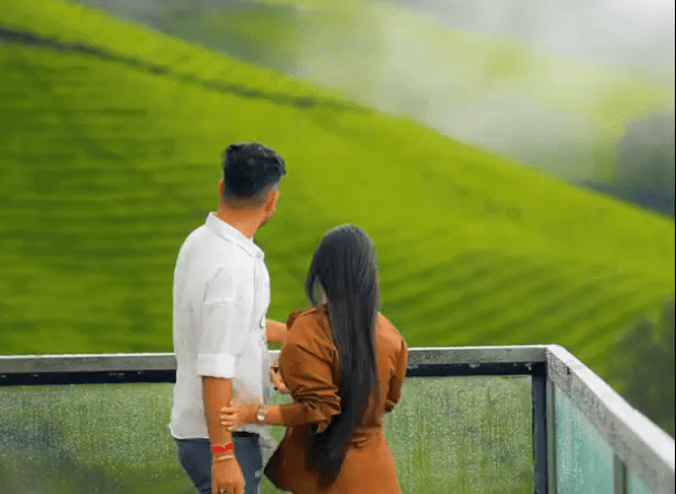 a couple standing on the balcony watching the green mountains