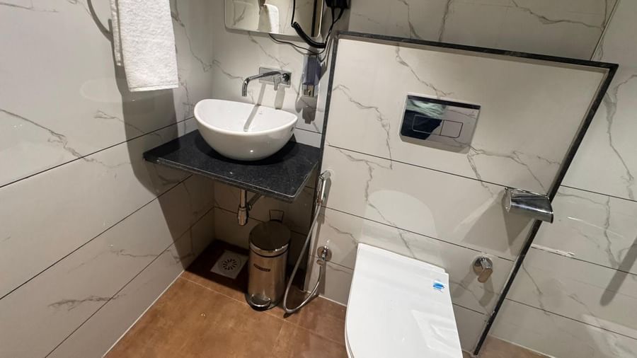 Sleek bathroom at Hotel Mumbai House, Vijay Nagar, Indore, fitted with modern fixtures, a wash basin, and marble wall accents for a stylish touch.