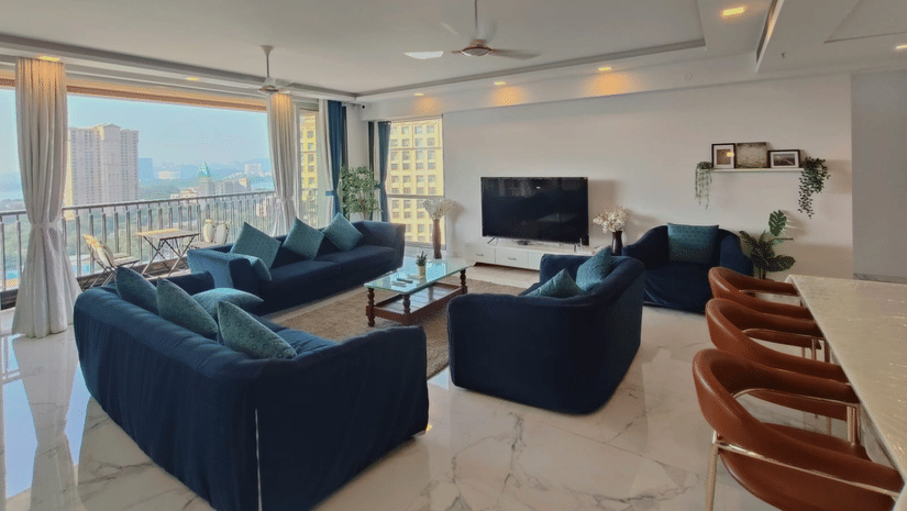 1hall and living room area of Maxxvalue Hotel, Chitranjan Tower, Powai with blue themed couch and a dining table in the corner of the room