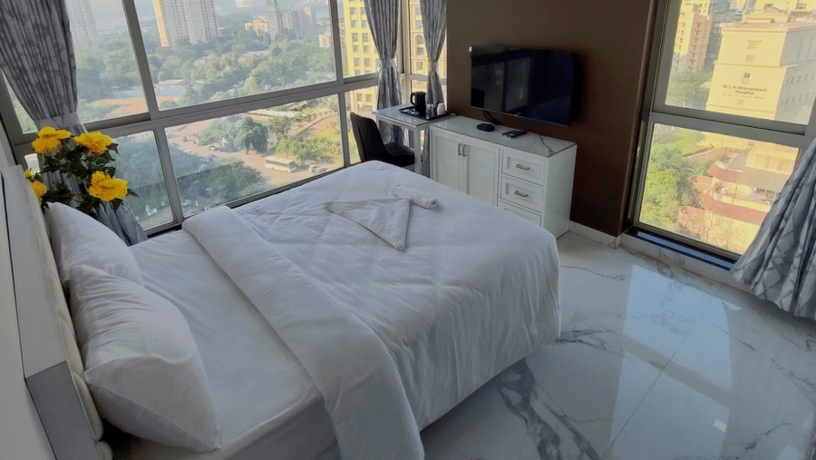 deluxe room at Maxxvalue Hotel, Chitranjan Tower, Powai with a posh bed and white linens along with floor-to-ceiling windows offering ciy view3