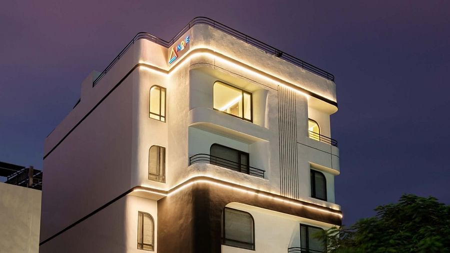 The facade of Indie Stays, Jaipur, glows brightly under night lights against the dark sky.