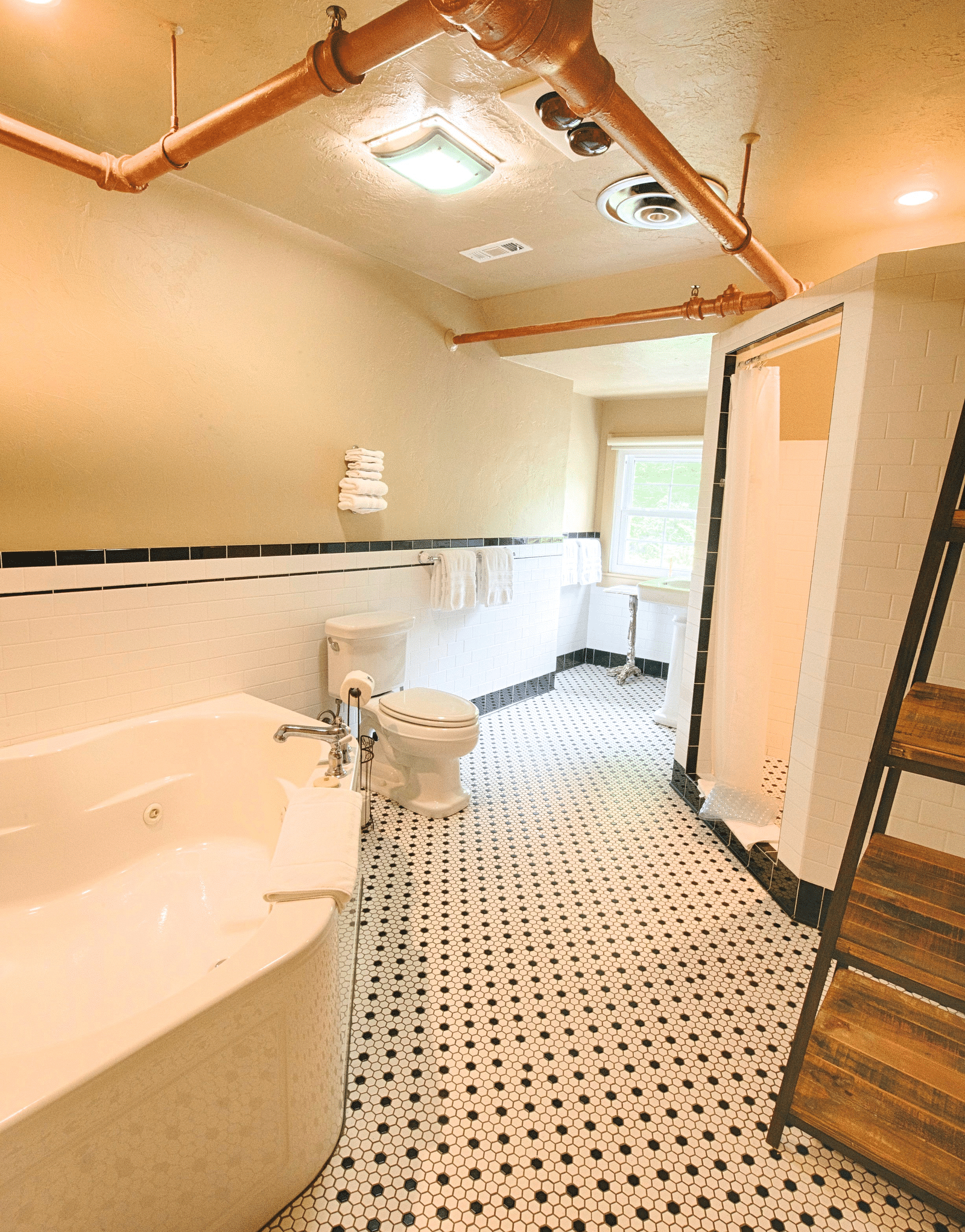 a wide angle view of the bathroom with black and white tiles along with a bathtub and a shower cubical - Historic Tapoco Lodge