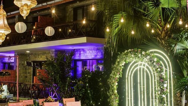 alt-text Romantic outdoor setting with fairy lights and a floral arch.