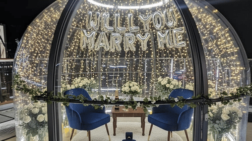 A round, dome-shaped dining booth or structure with glass panels and a detailed metallic framework, containing a small dining table and chairs | Pride Elite Chhatrapati Sambhajinagar