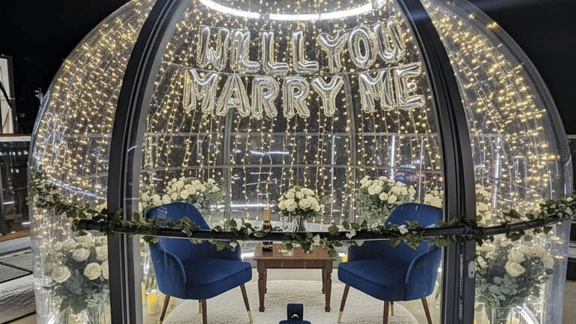 A round, dome-shaped dining booth or structure with glass panels and a detailed metallic framework, containing a small dining table and chairs | Pride Elite Chhatrapati Sambhajinagar