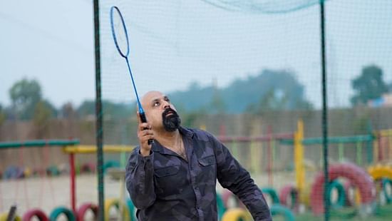 A man playing badminton at Themis Mudhouse - A Nature's Retreat Resort & Wellness
