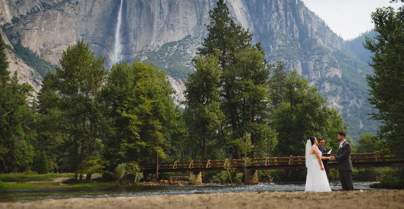 A newly wed couples holding hands with the Yosemite in the backdrop - Narrow Gauge Inn - A Serenite Hotel Near Fish Camp.