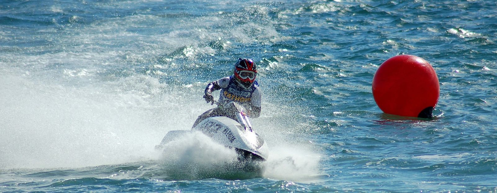 a person jet skiing on a waterbody with floating devices behind him 