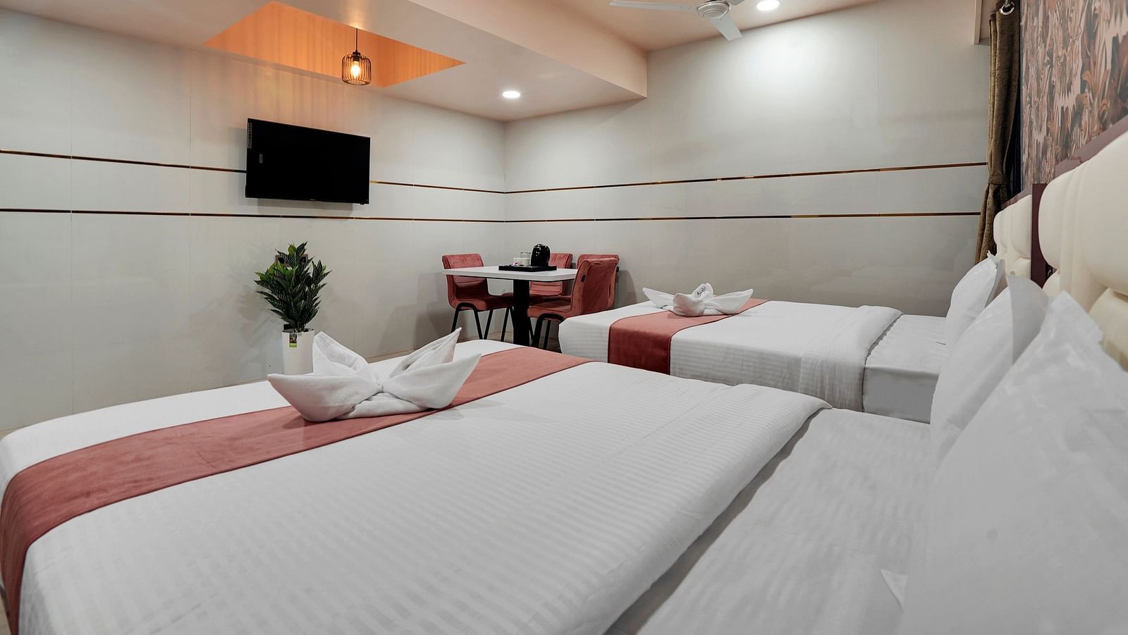 Two king size beds placed in front of television in Family Room at Hotel Regal Heaven, Pune.