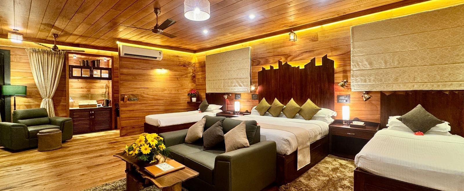 A warm room featuring a double bed, armchairs, a small table, and wooden panelling - BluSalzz Collection - Tranquil Resort, Wayanad