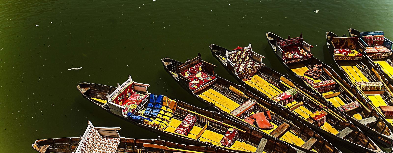 an image with several boats lined up at a dock, with people relaxing inside. The water is calm, and the overall atmosphere is peaceful and serene.