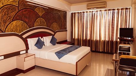 full view image of the executive room at the grand krishna room in bengaluru featuring a double bed and shiny curtains at the far end of the room