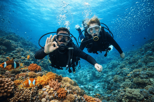 A couple of scuba divers underwater near reefs with fish swimming around