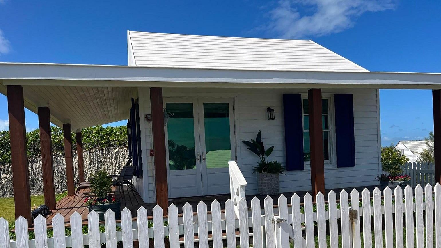 One-story house with a picket fence surrounding the front yard. Shutters frame the windows and a palm tree is visible to the left | Abaco Inn