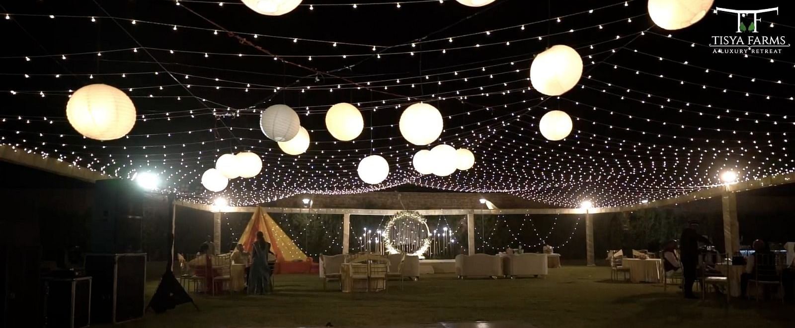 Circular stage at Tisya Farms, Gurgaon with surrounding seating and overhead hanging lights at night.