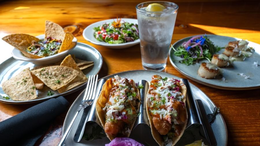 Mexican-inspired dish with tacos, grilled shrimp, pita, and salad served with lemon water at Narrow Gauge Inn.