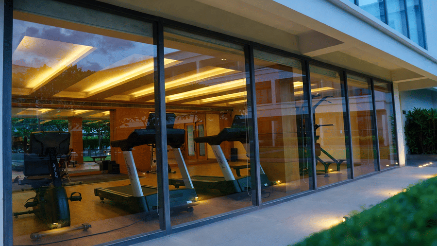 Modern gym and fitness centre with treadmills seen through glass windows at Kiranshree Grand Hotel.