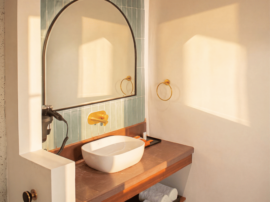 A close-up view of a bathroom vanity with a white washbasin, an arched mirror, and a wooden countertop at The Sierra - By The Lake.