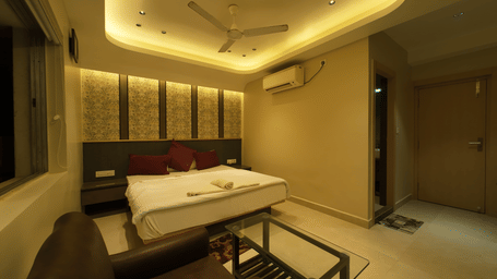 Deluxe Classic Room with a large bed, warm lighting, and a small glass table at Hotel Seagull Digha