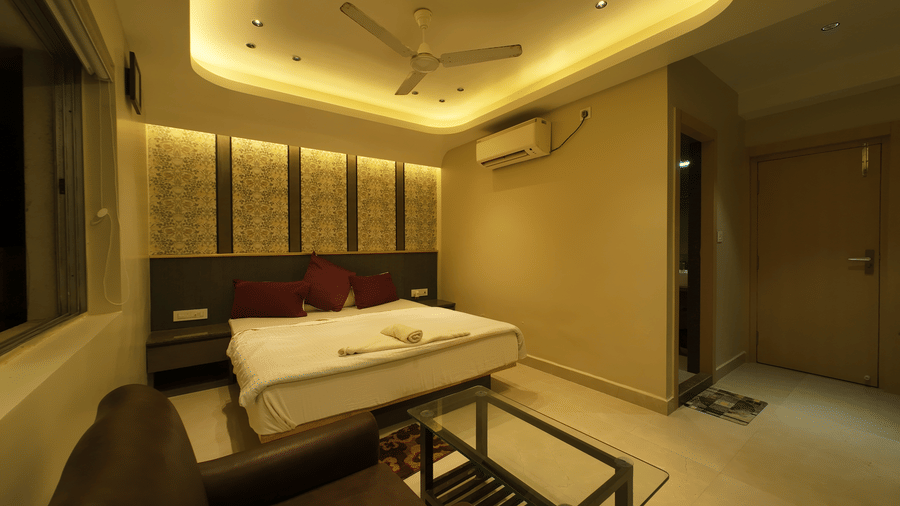 Deluxe Classic Room with a large bed, warm lighting, and a small glass table at Hotel Seagull Digha