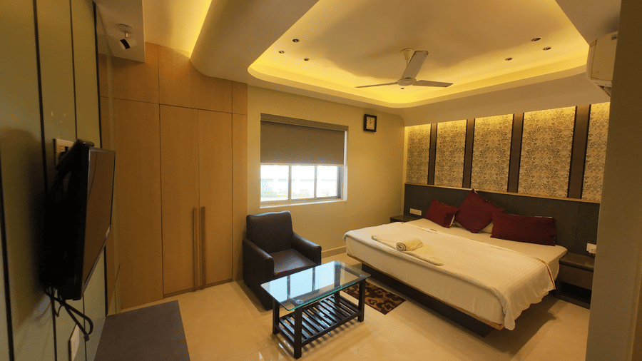 Deluxe Classic Room with a large bed, a television mounted on the wall, and a small sitting area at Hotel Seagull Digha