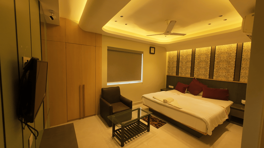 Deluxe Classic Room with a large bed, a television mounted on the wall, and a small sitting area at Hotel Seagull Digha