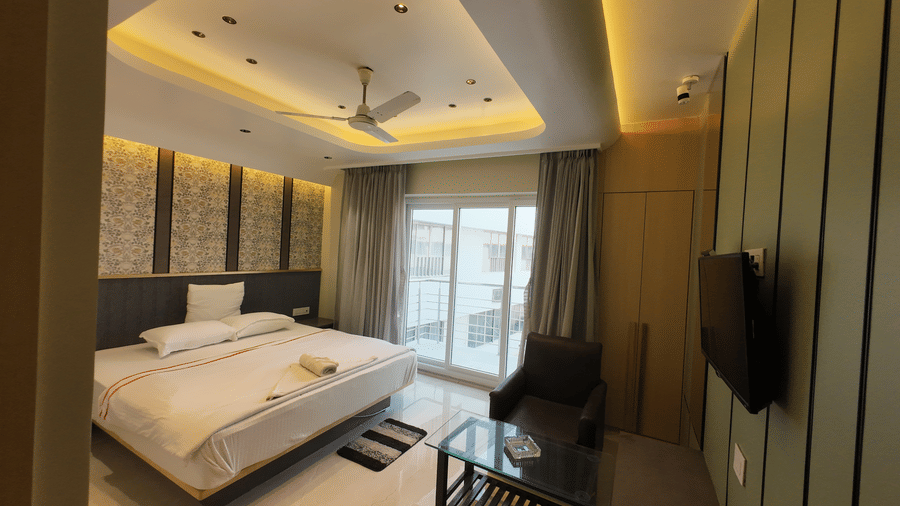 Deluxe Classic Varanda Room with a large bed, wall-mounted TV, and window with curtains at Hotel Seagull Digha