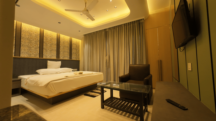 Deluxe Classic Varanda Room with a large bed, contemporary lighting, and a small seating area at Hotel Seagull Digha