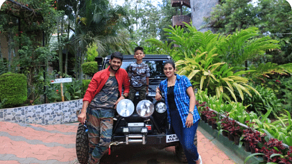 Image of three people standing in front of a car posing for a photo.