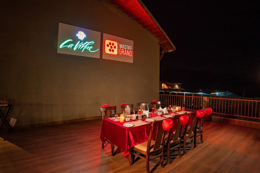  Rooftop dining area with tables and chairs arranged for an evening gathering or event - Mastiff Grand La Villae Resort, Lonavala