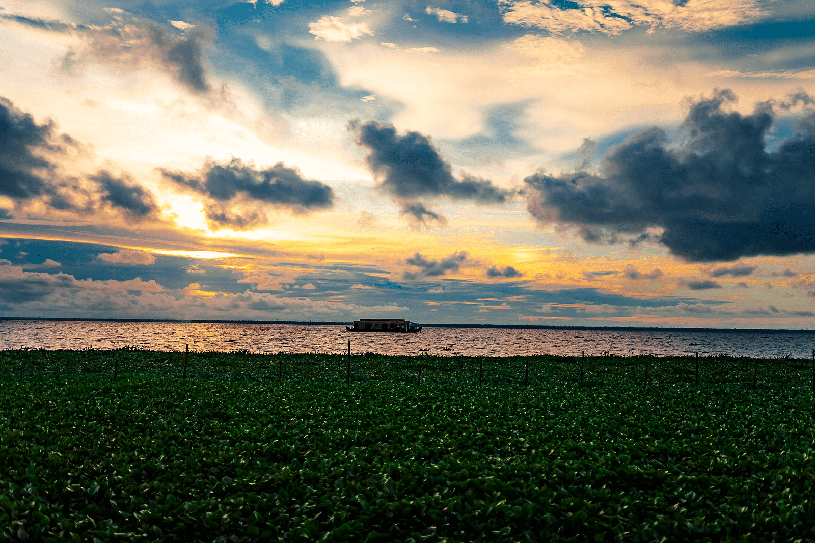 an image of Evening view after the sun set with a boathouse in the water - Rhythm Kumarakom