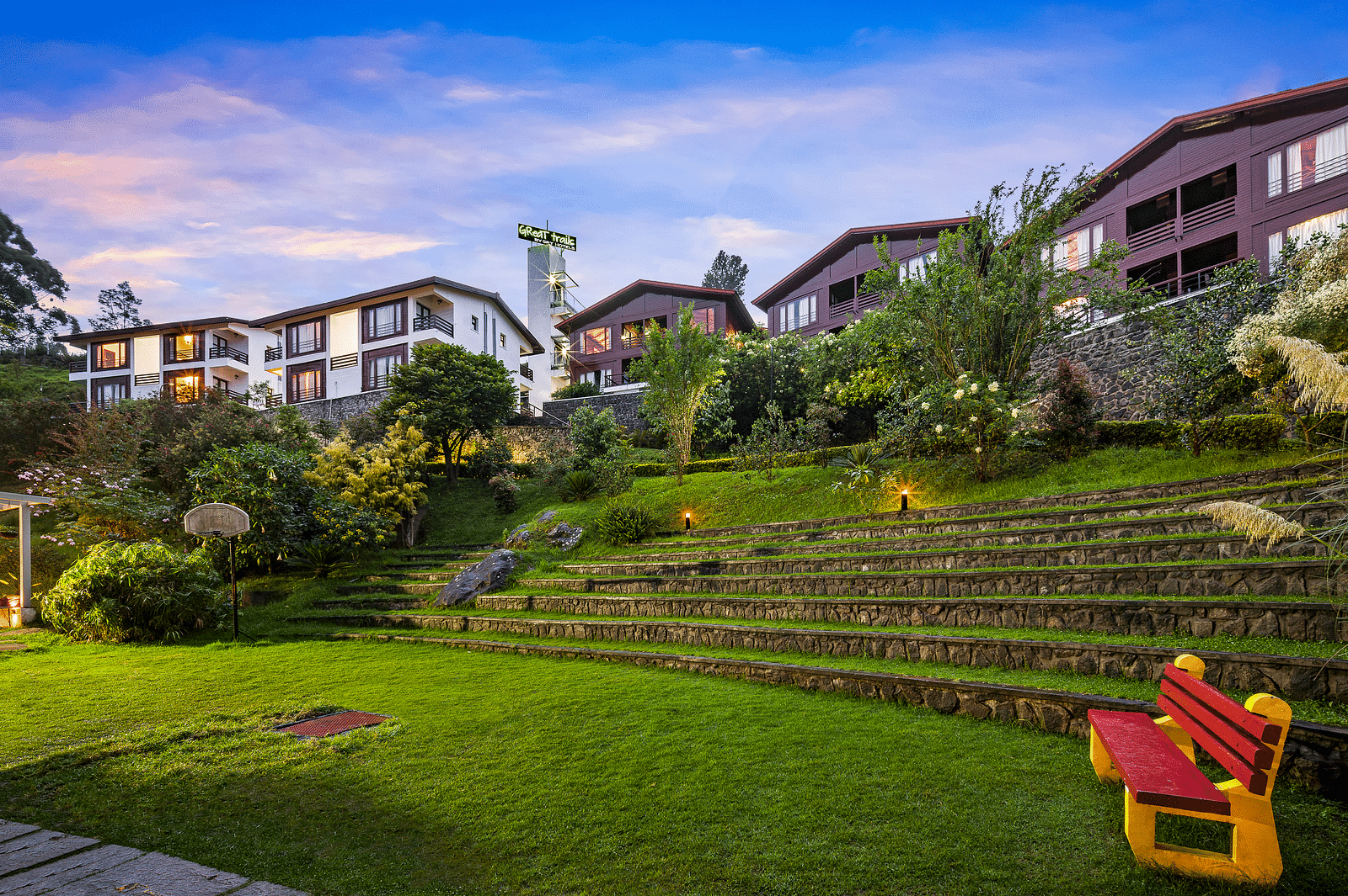 Exterior view of the hotel with lush greenery with the hotel buildings in the background - GReaT Trails Kodaikanal By GRT Hotels