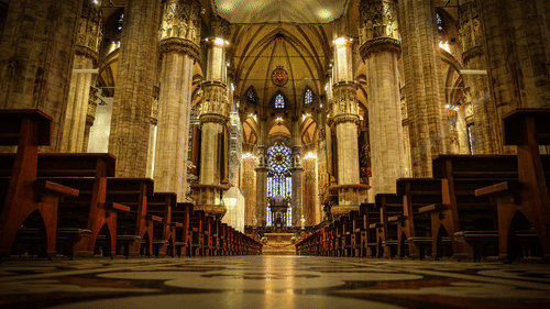 an alter of a church with a decorated ceiling and warm interior arrayed with sitting areas
