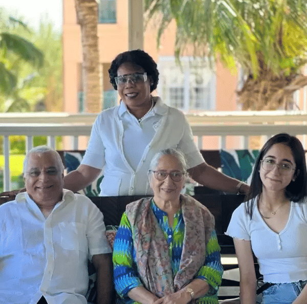 A family of 4 featuring with big smiles on their faces as they pose towards the camera.