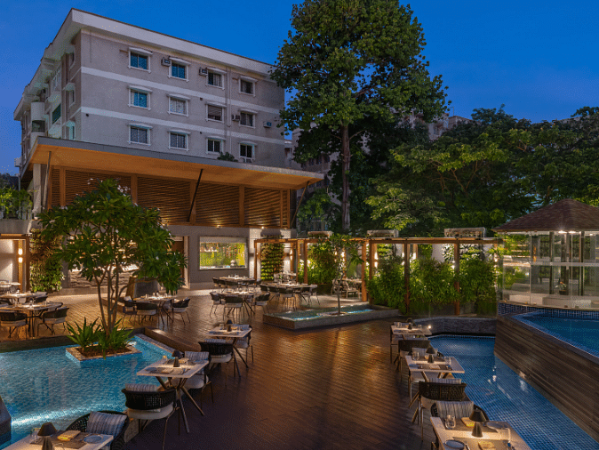 An outdoor swimming pool with a bar and lounge area, surrounded by lush greenery.