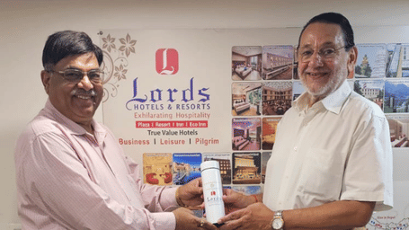 Two men smile for a photo while holding a small box.