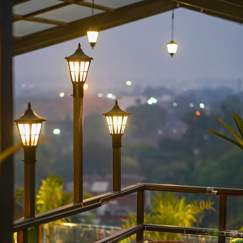 two chairs facing each other on a terrace with warm lights besides it on a late evening