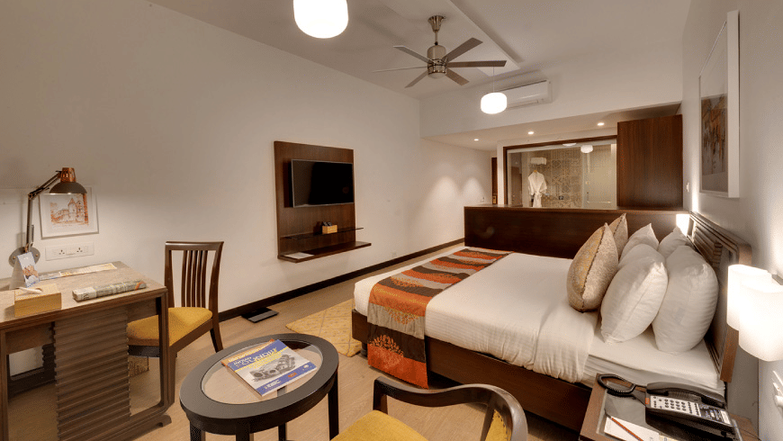 Spacious Studio Room bedroom at Trance Sunderban Resort featuring a double bed, polished floors, and large windows opening onto a balcony.