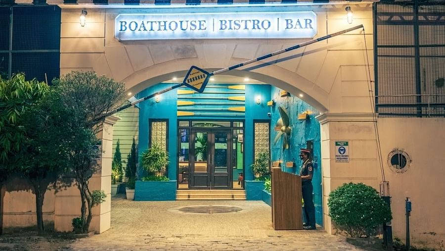 Nighttime view of the entrance to the Boathouse Bistro & Bar, with a sign above the door and a security guard standing by.