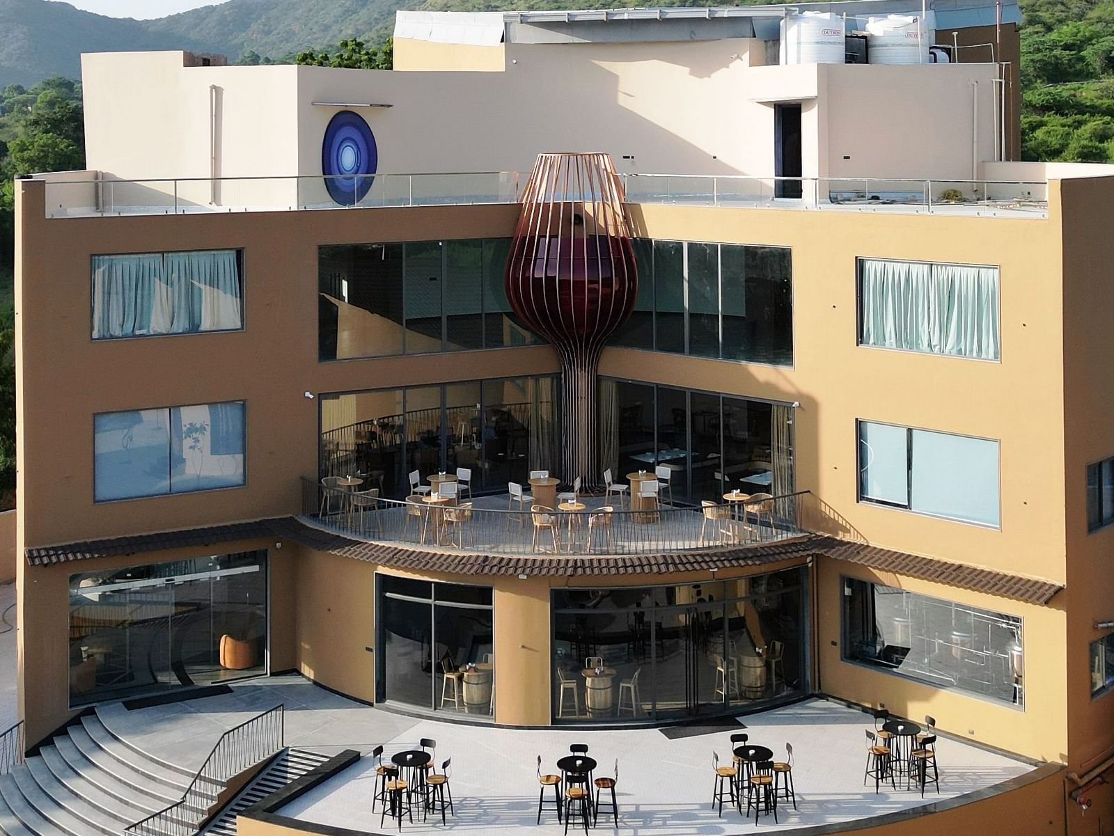 The Qualia Resort Club & Brewery, Udaipur with a terrace and outdoor seating is shown in daylight.