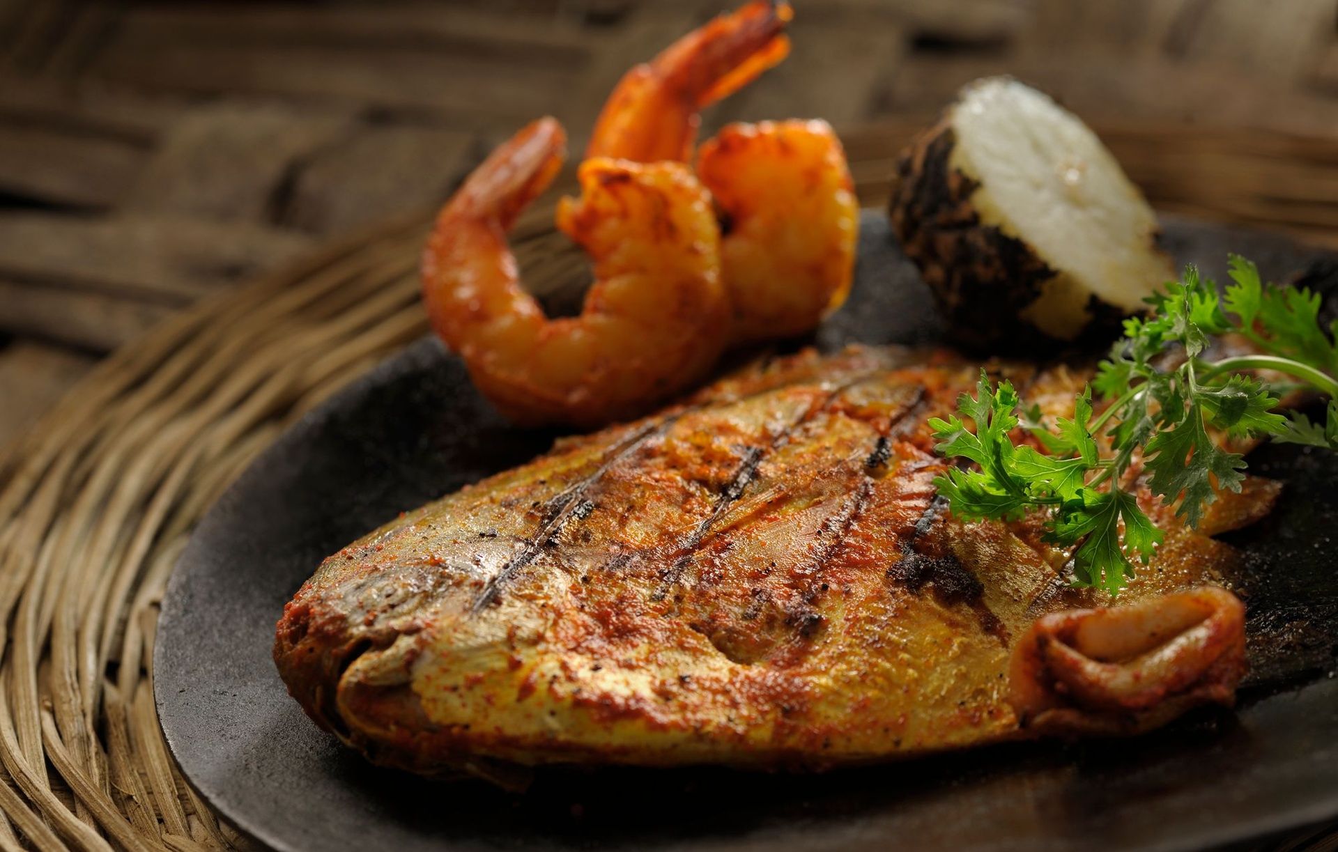 Grilled fish with shrimp, potato, and parsley garnish.