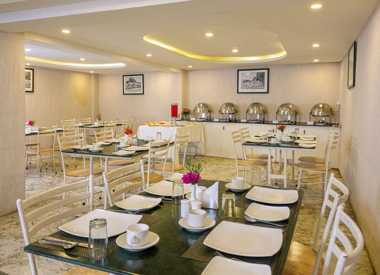 Elegant hotel dining area with white chairs and set tables for a breakfast buffet  |  Mango Hill Central, Chennai