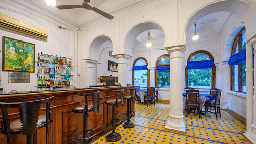 Various bar stools in front of a bar table with drinks in the background - The Baradari Palace