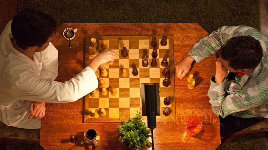 Overhead view of two people playing chess on a wooden table with warm lighting - Brewery Gulch Inn & Spa